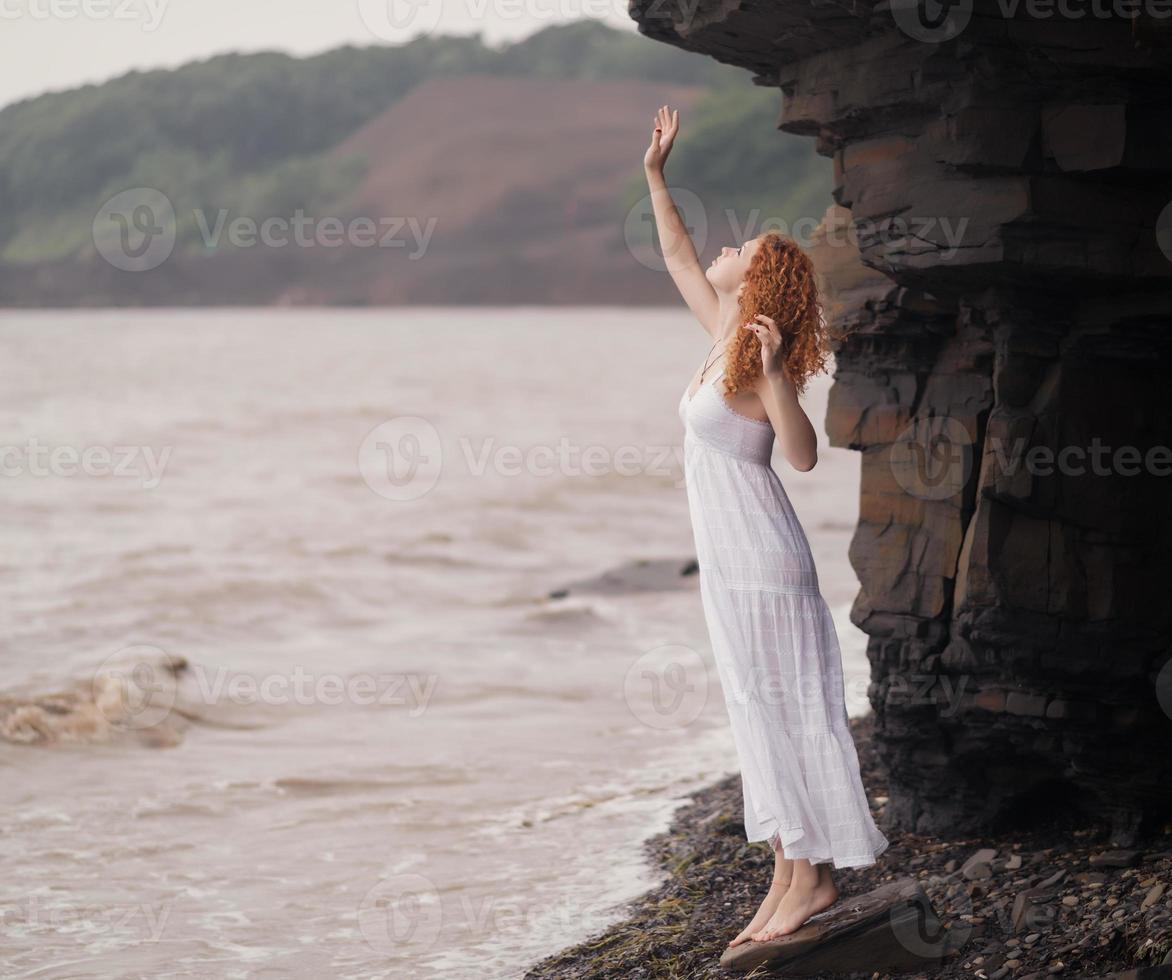 femme en robe blanche, debout sur la plage. photo