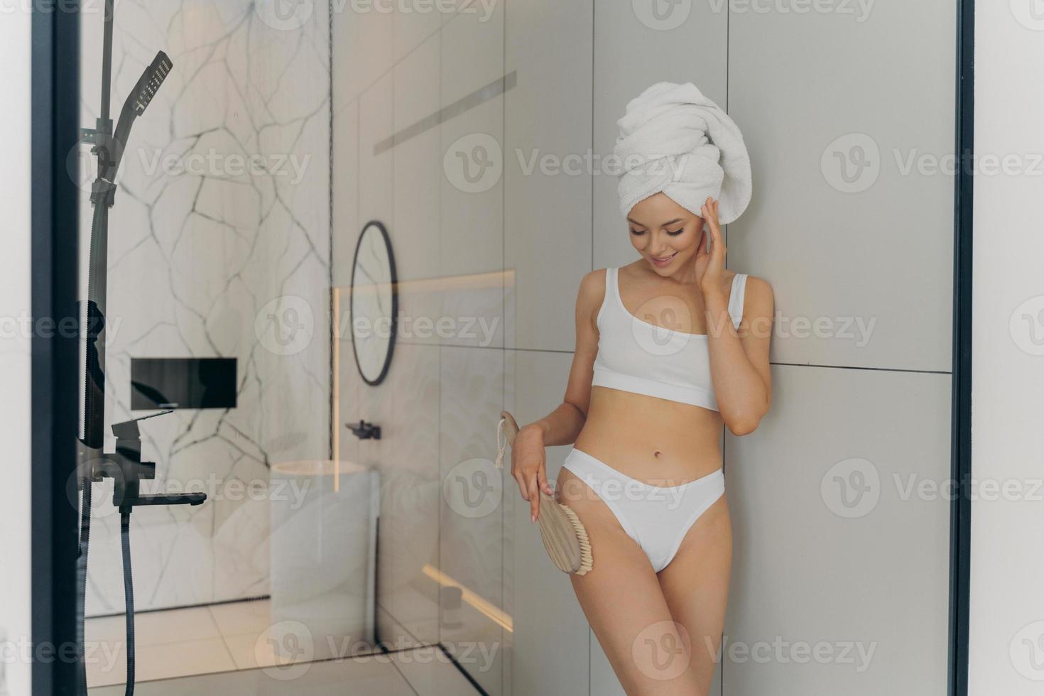 beau modèle féminin avec une brosse sèche dans sa main relaxante dans la salle de bain photo