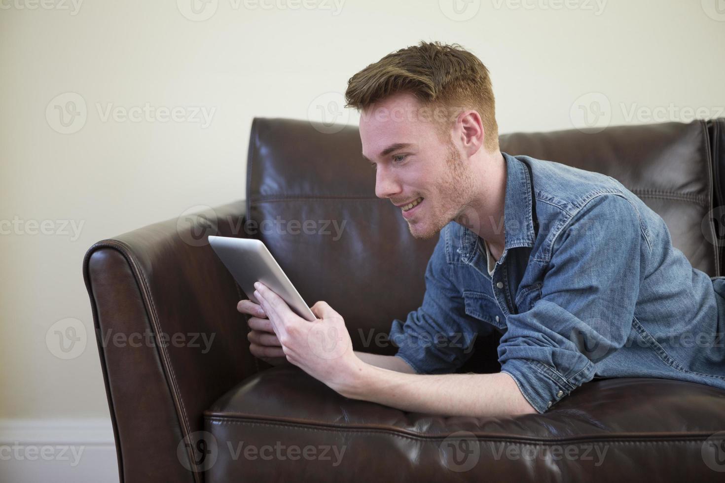 homme caucasien à l'aide de tablette numérique à la maison sur le canapé. photo