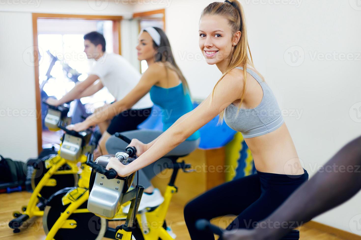 jeunes avec vélo de fitness dans la salle de gym. photo