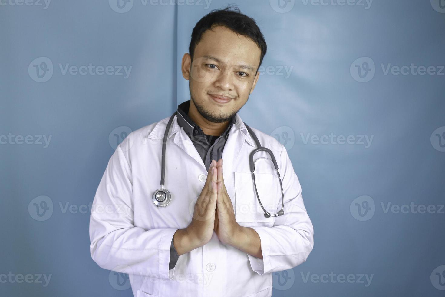 un jeune médecin asiatique sourit et fait un geste de salutation photo