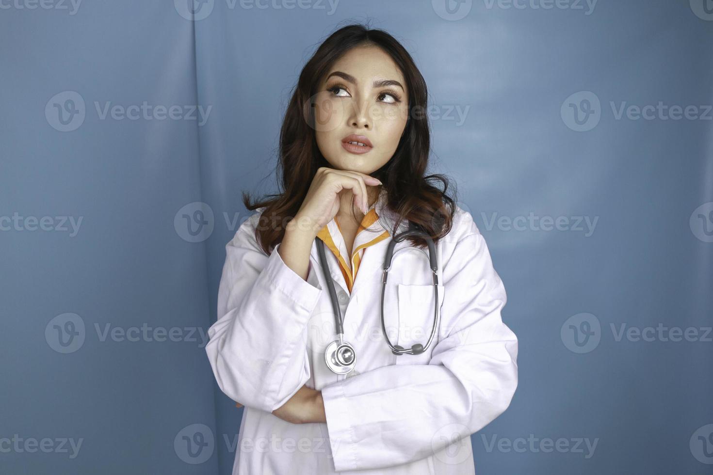 Jeune femme médecin sur fond isolé en pensant à une idée photo