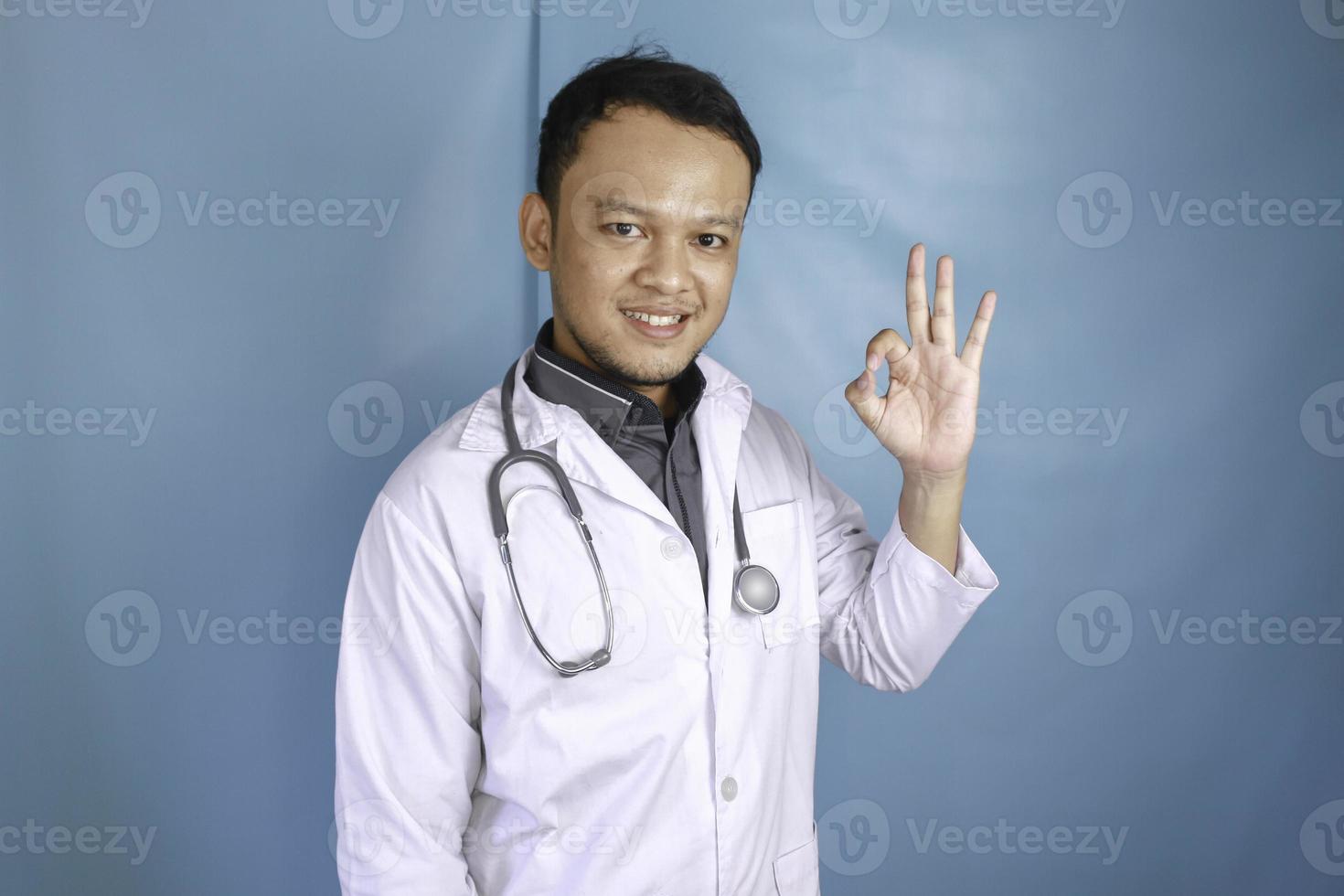 une jeune femme médecin asiatique sourit et montre un signe ok. photo