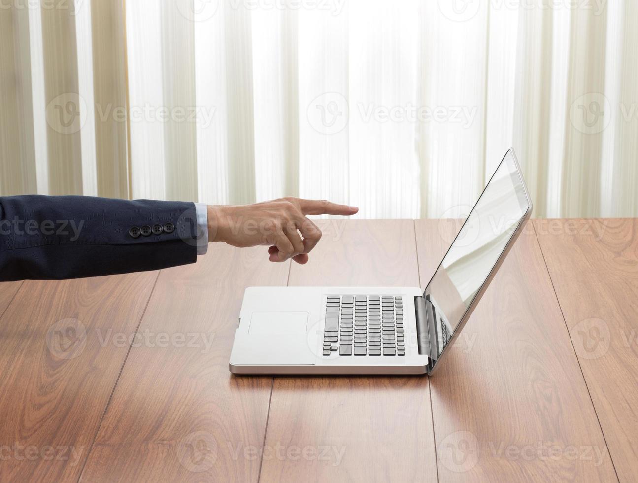 main d'homme d'affaires pointant vers un ordinateur portable photo