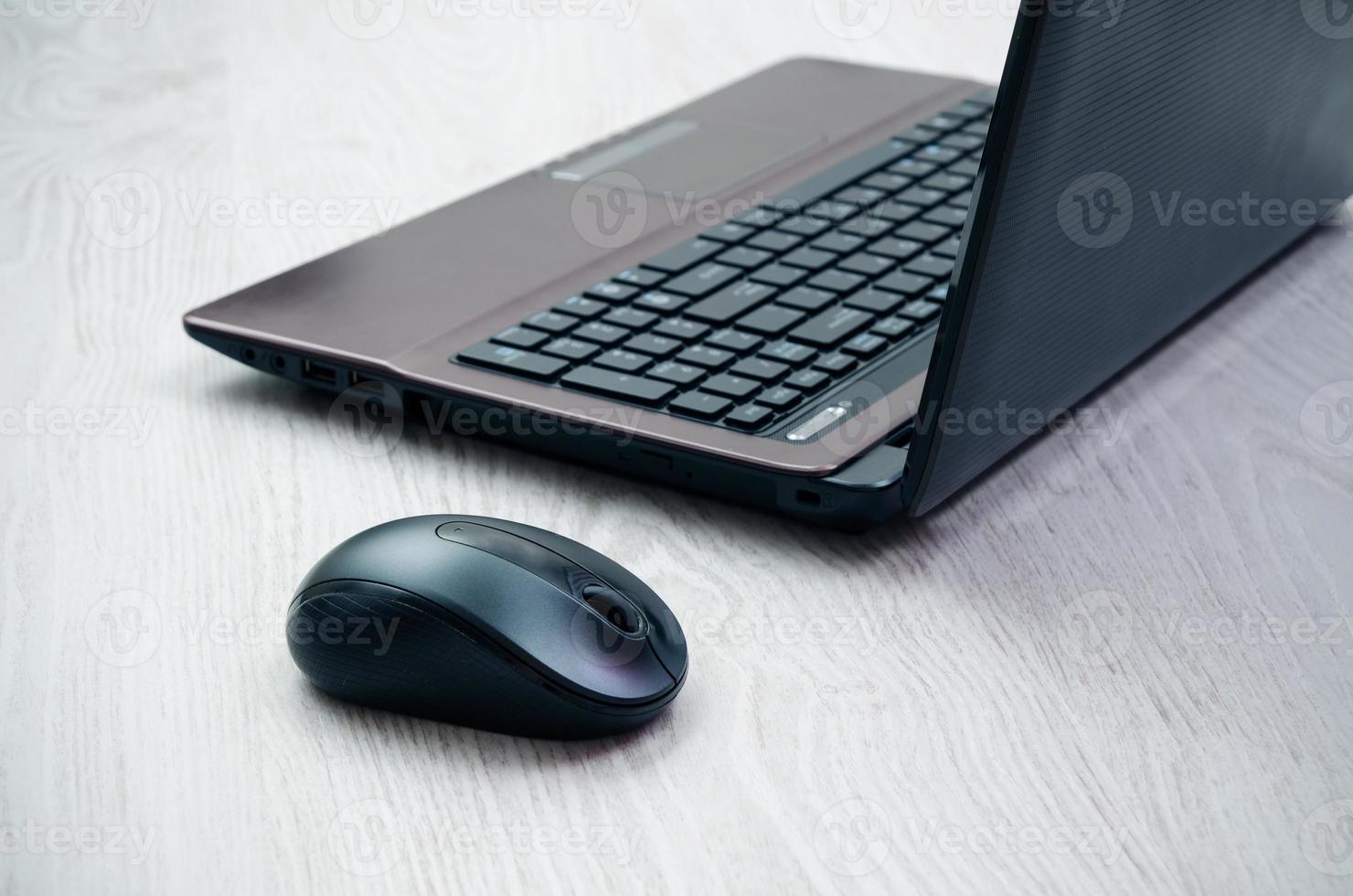 ordinateur portable moderne et souris sur un bureau en bois clair photo