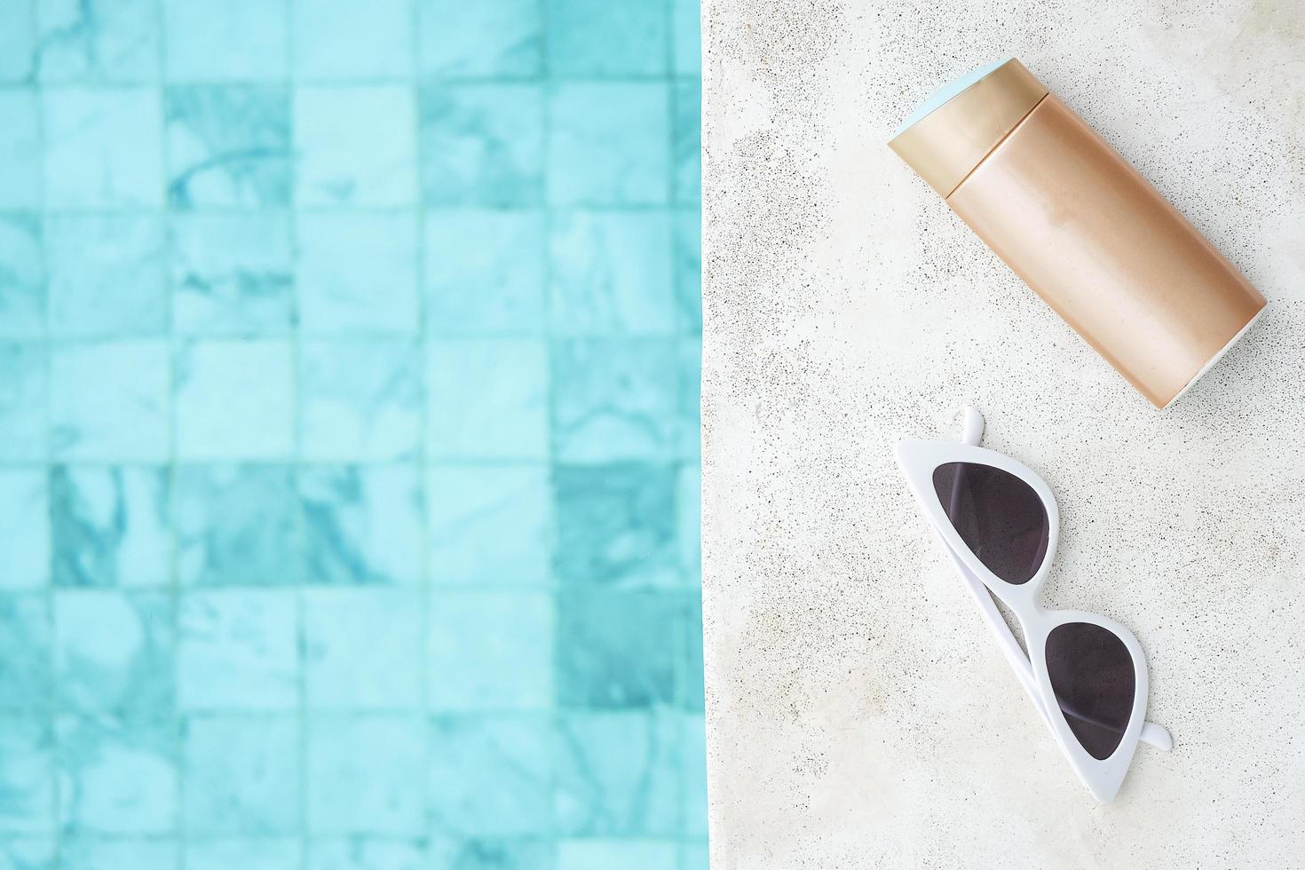 lunettes de soleil blanches, bouteille de crème solaire et chapeau près de la piscine dans un hôtel de luxe. voyage d'été, vacances, vacances et concept de week-end photo
