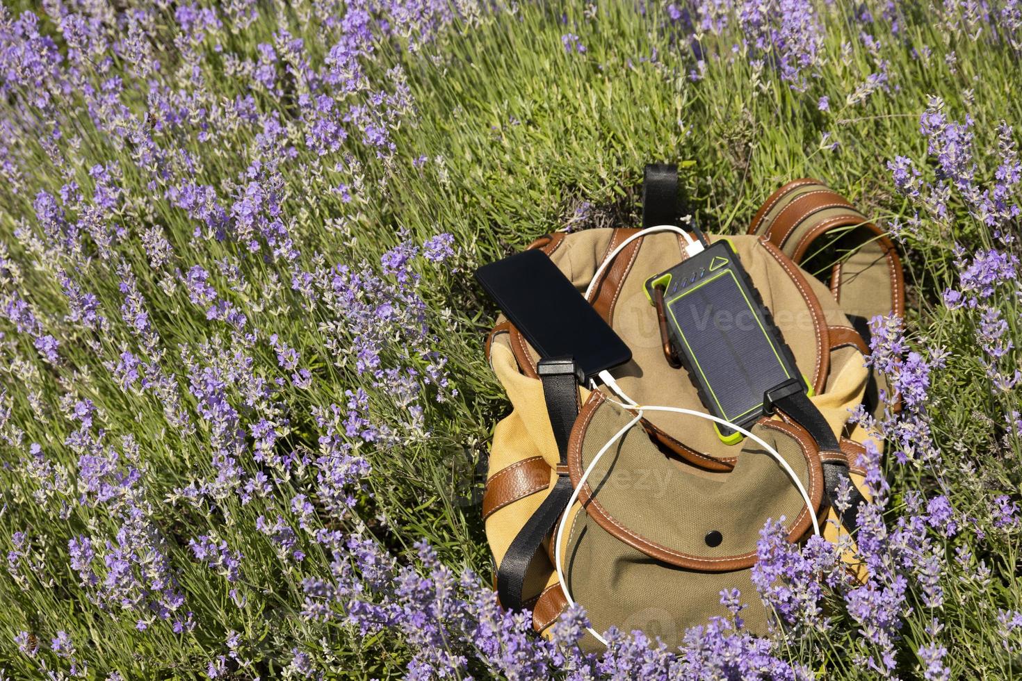 le smartphone est chargé à l'aide d'une banque d'alimentation de chargeur portable sur un panneau solaire, sur le fond d'un sac à dos lors d'un voyage photo