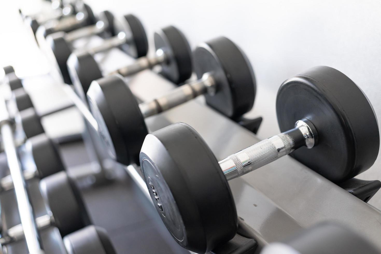 debout avec des haltères. salle de sport et de remise en forme. équipement de musculation. ensemble d'haltères noires, de nombreux haltères sur rack dans un centre de remise en forme sportive photo