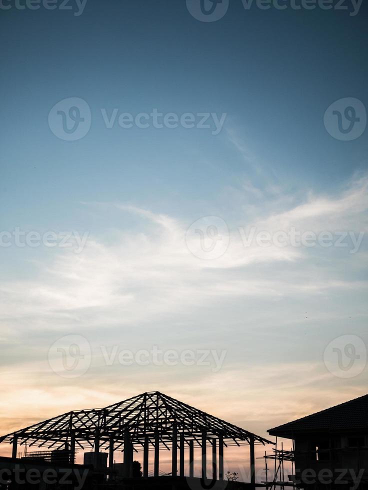 bâtiment de maison de silhouette au fond de coucher de soleil de chantier de construction photo