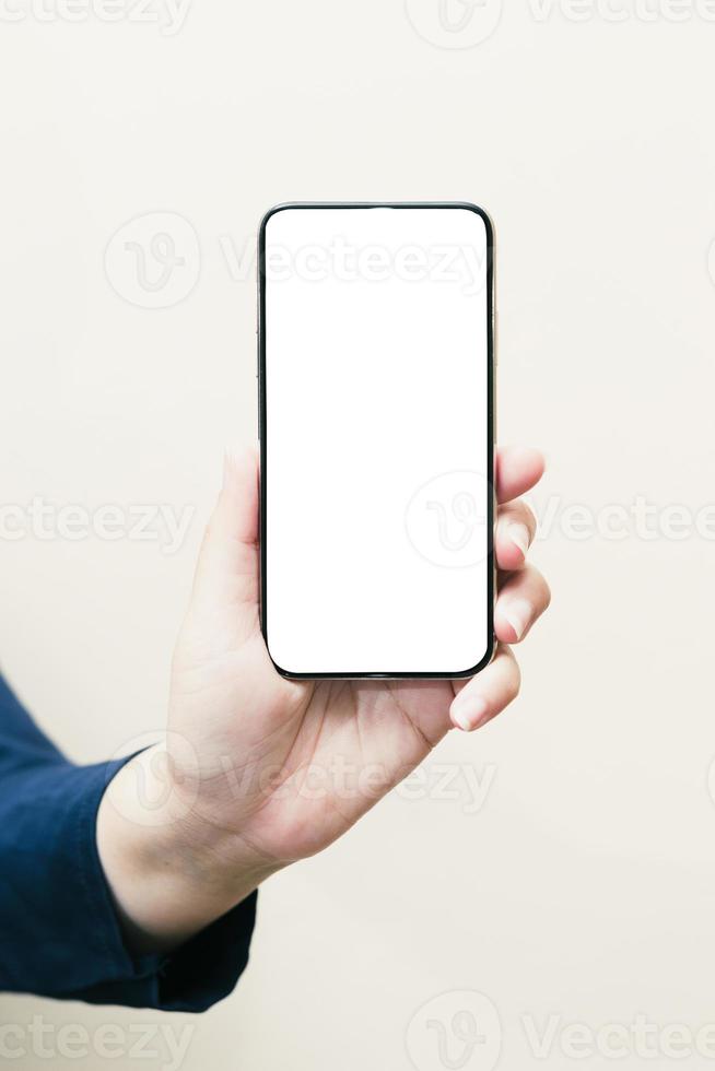 la main gauche d'une femme blanche montrant un téléphone portable ou un téléphone portable noir et un écran blanc pour le contenu de la maquette sur un fond blanc isolé ou découpé. photo