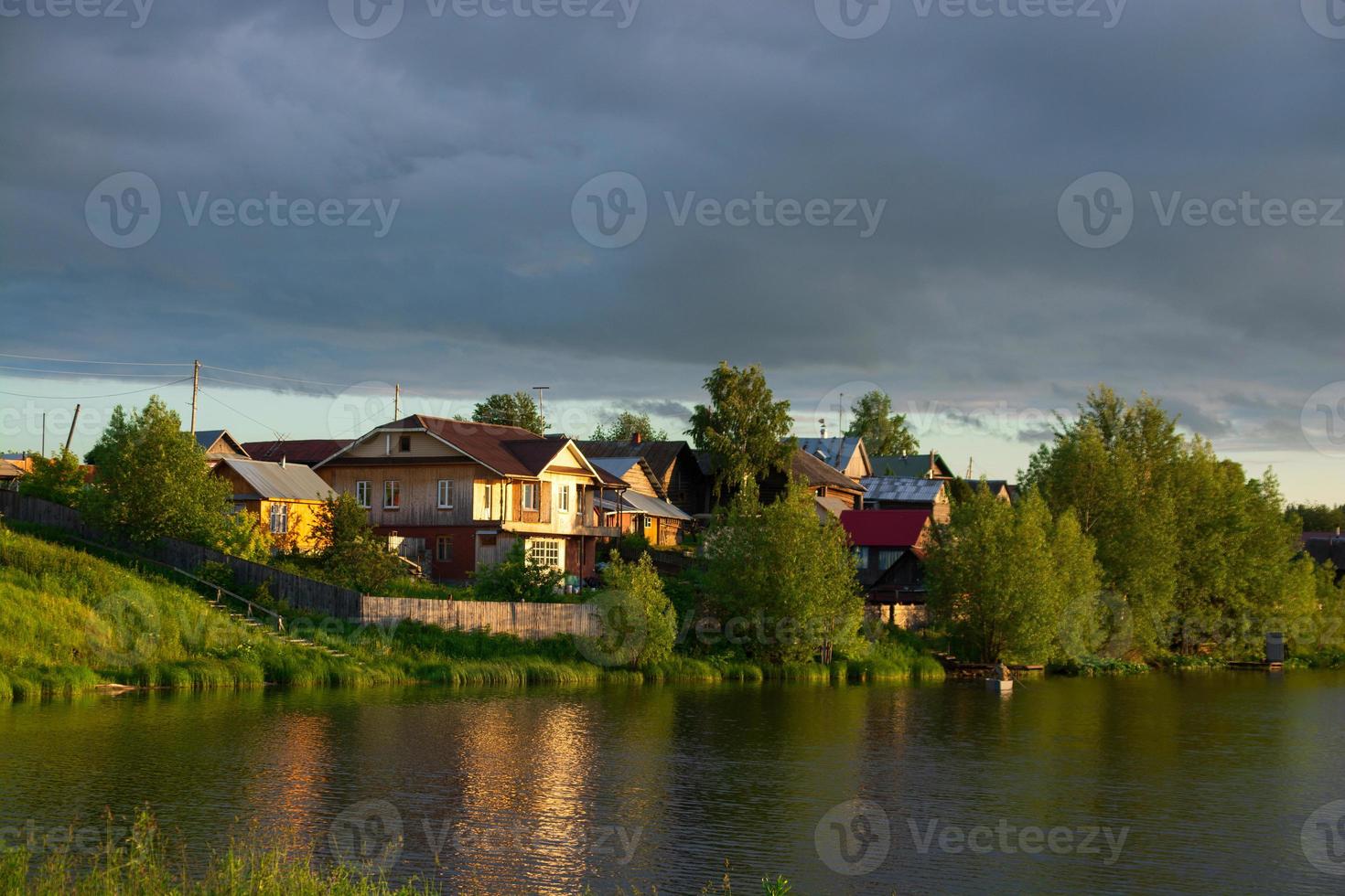 un village au bord de la rivière avec une herbe verte brillante et un beau ciel. photo