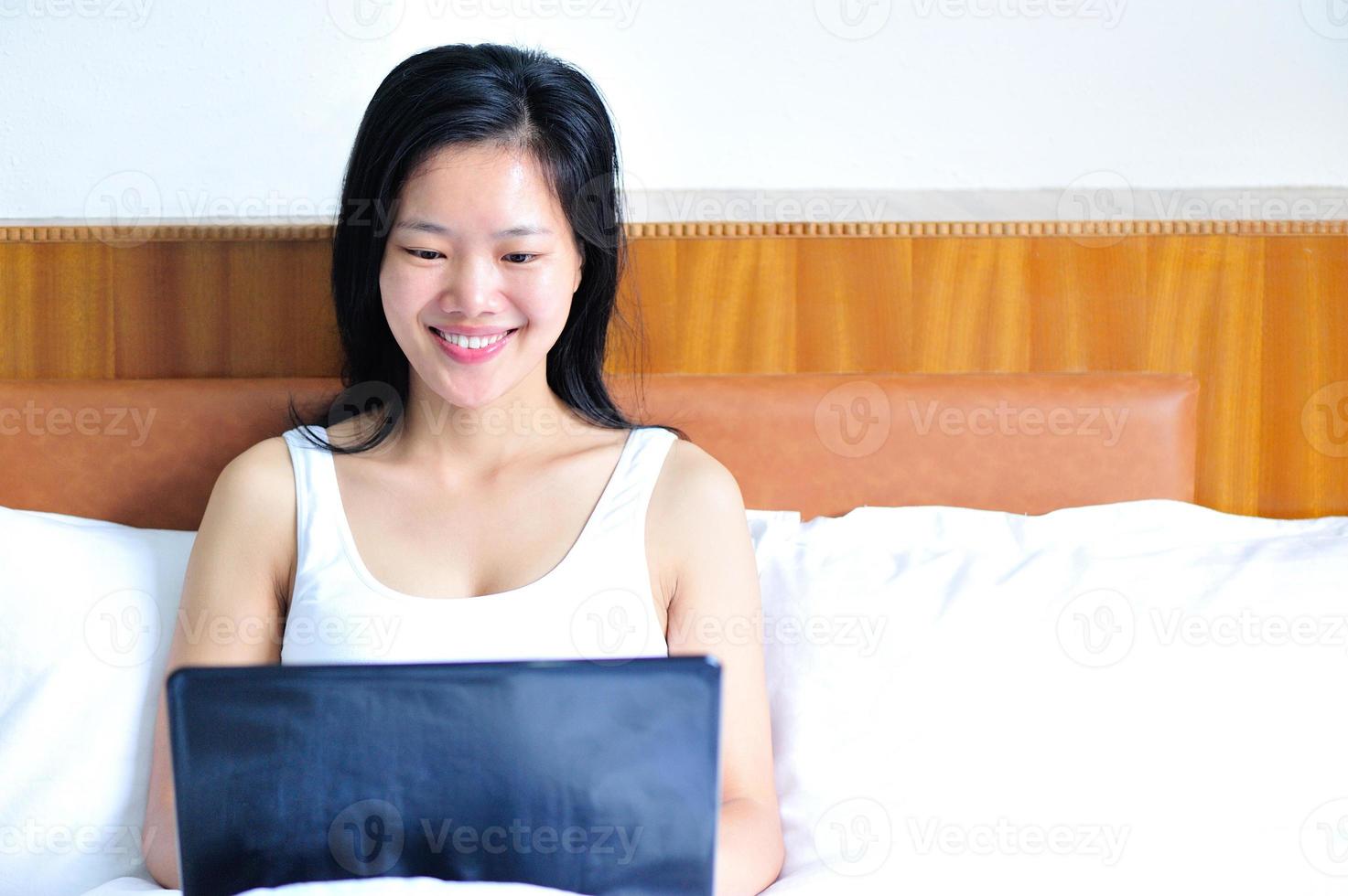 femme souriante, s'appuyer, lit, utilisation, elle, ordinateur portable photo