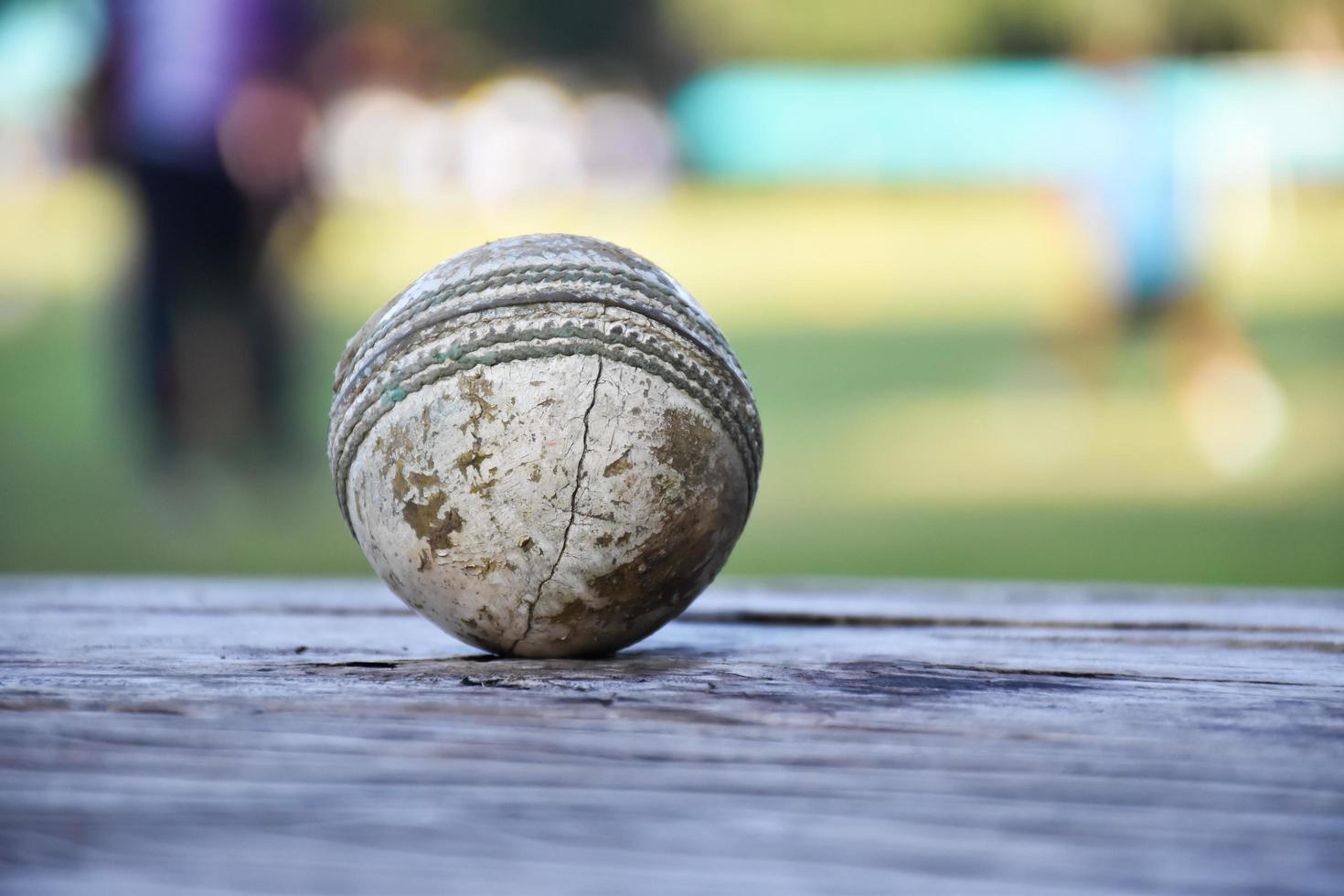 anciens équipements de sport de cricket d'entraînement sur sol sombre, balle en cuir, guichets, casque et chauve-souris en bois, mise au point douce et sélective, amateurs de sport de cricket traditionnels dans le monde entier. photo