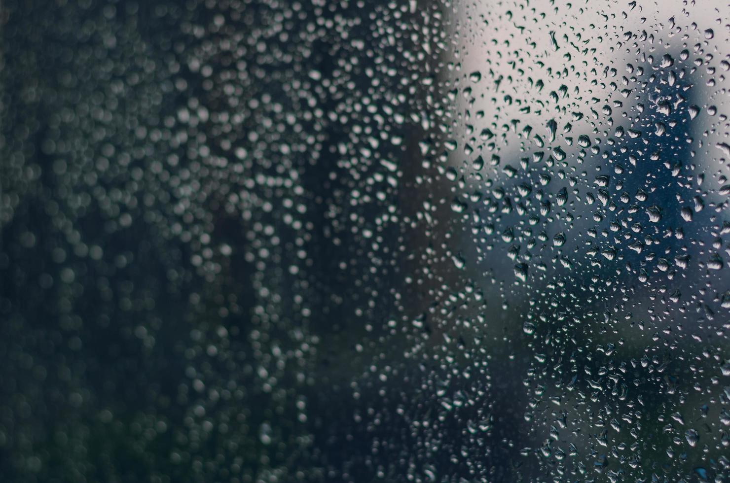 flou et mise au point de la goutte de pluie sur la fenêtre en verre. photo