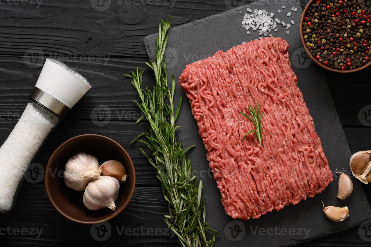 viande crue fraîche ou viande de poulet hachée sur une planche à découper en bois avec thym, épices et ail. fond en bois rustique. vue de dessus. espace de copie. photo