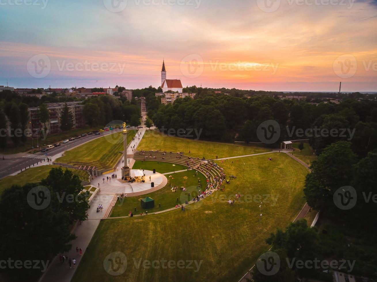 siauliai, lituanie, 2021 - vue panoramique aérienne du panorama de la ville de siauliai en été avec un magnifique coucher de soleil et les gens apprécient un concert en direct de la célèbre statue du garçon doré photo