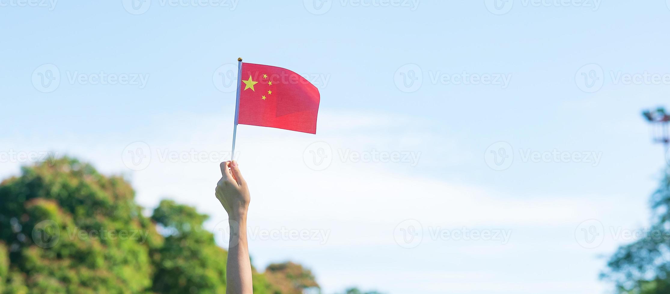 main tenant le drapeau de la chine sur fond de ciel bleu. fête nationale de la république populaire de chine, jour férié de la nation publique et concepts de célébration heureuse photo