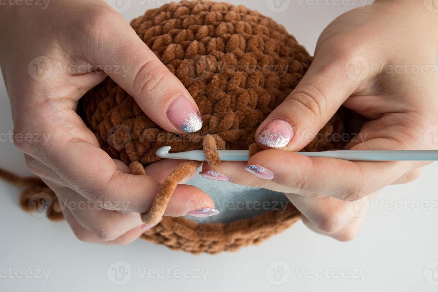 le processus de tricotage de jouets pour enfants à partir de fils en peluche. tête à tricoter. Fait main photo