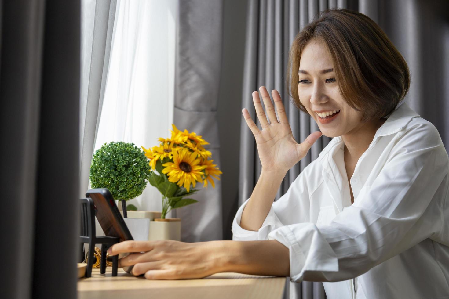 femme asiatique ayant un appel vidéo à l'aide d'un téléphone portable tout en étant confortablement assise à la maison pour un concept de rencontre et de technologie en ligne photo