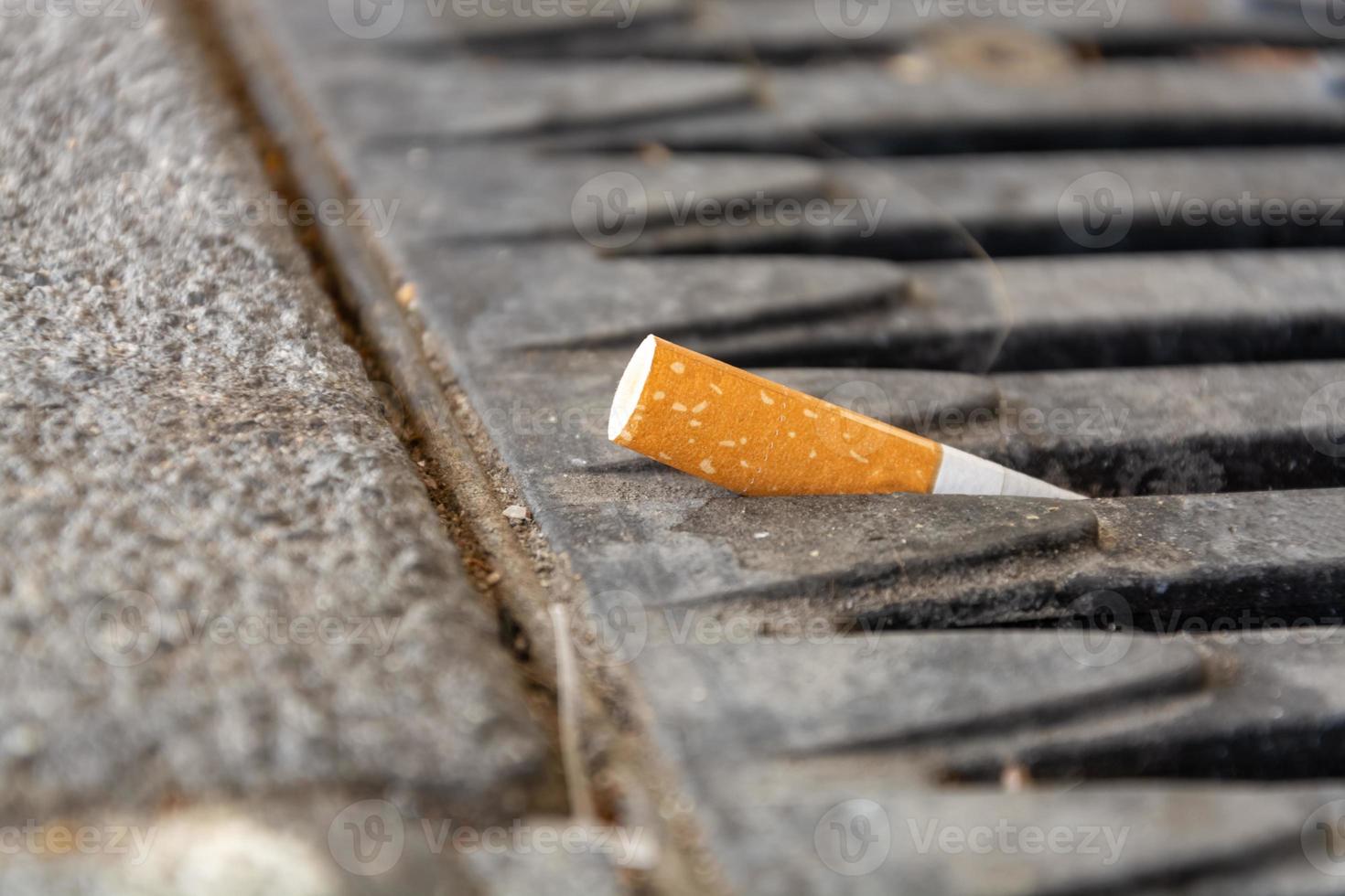 Mégot de cigarette posé sur une grille métallique photo