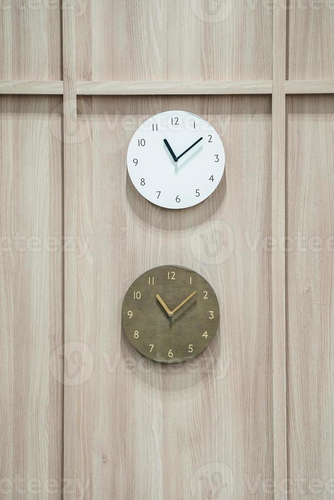 deux horloges de différence s'accrochent à un fond en bois. photo