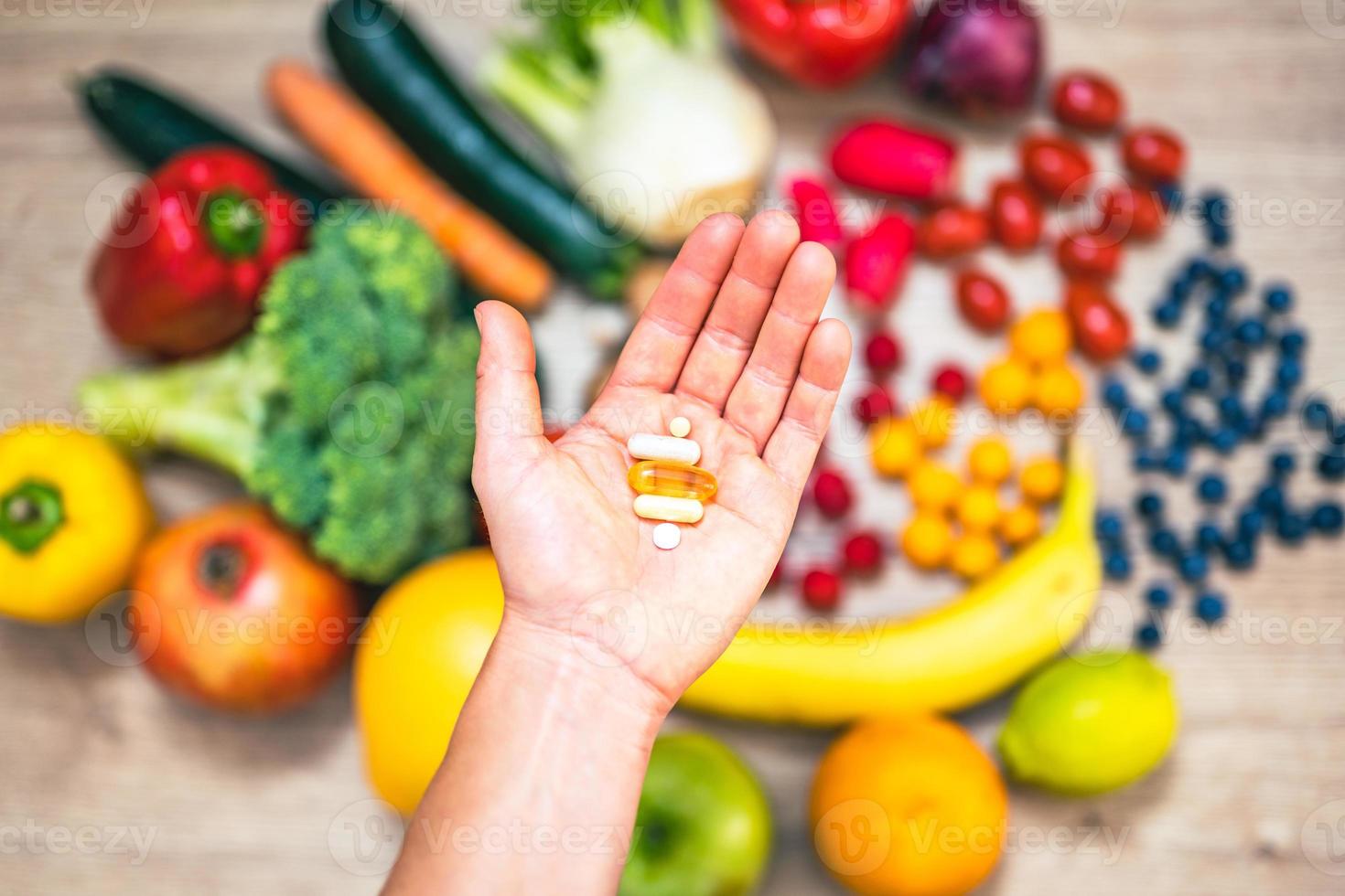 main tenant des compléments alimentaires sur des légumes et des fruits pour un mode de vie sain photo