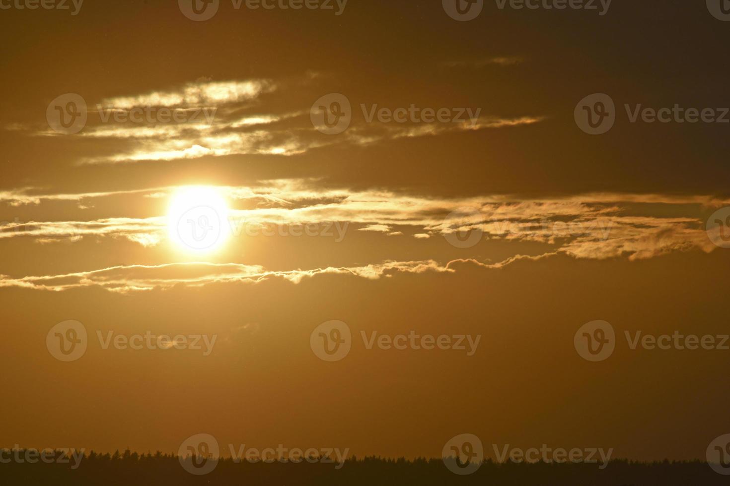 le disque solaire et les nuages du soir sur le fond de la forêt photo