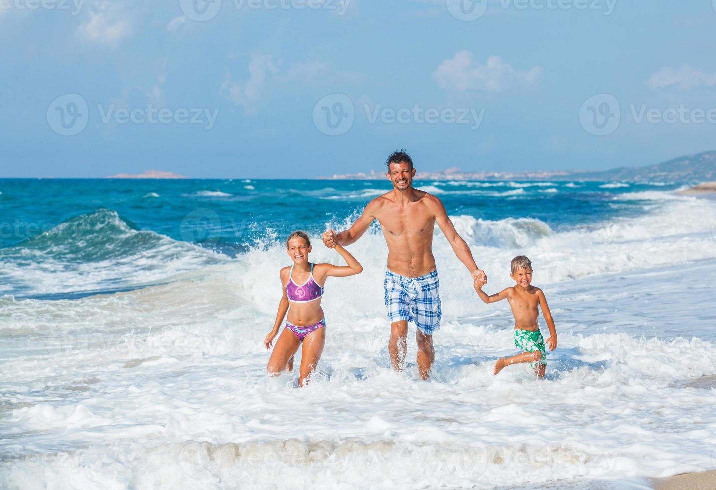 père et enfants jouant sur la plage photo