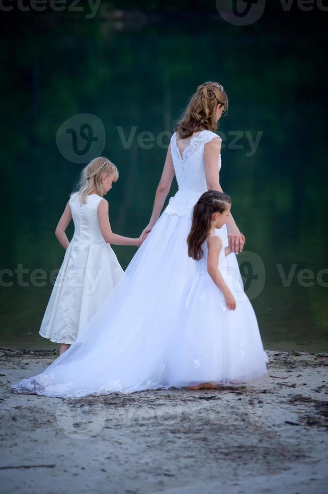 mariée mène des filles de fleur au bord de l'eau photo