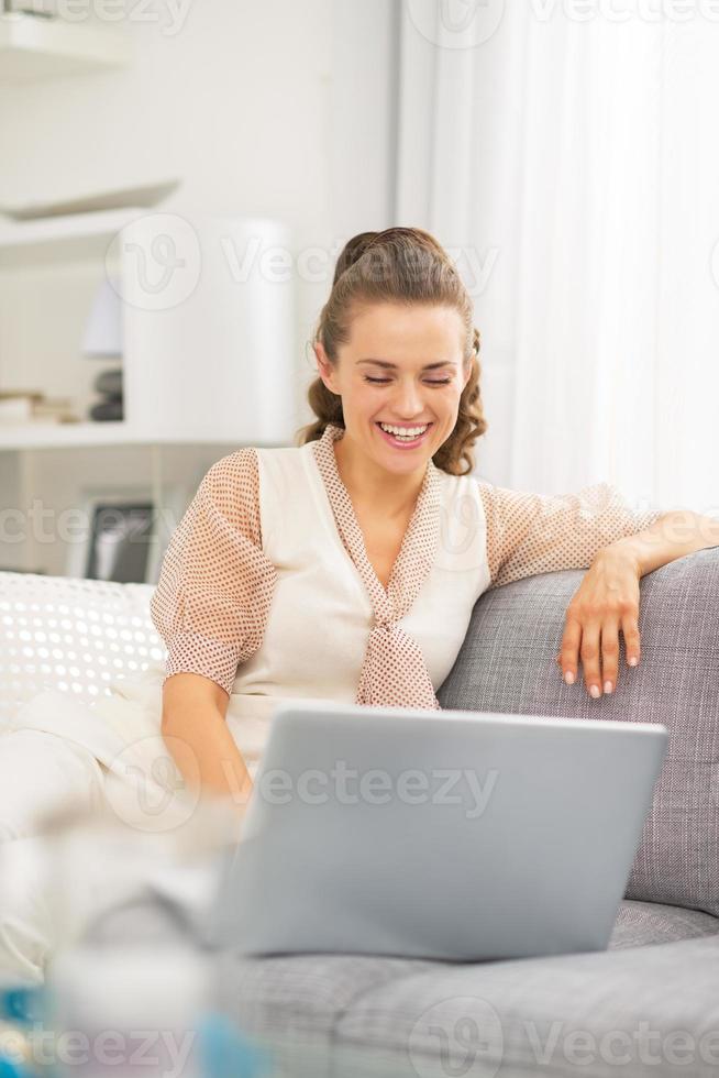 heureuse jeune femme au foyer à l'aide d'un ordinateur portable dans le salon photo