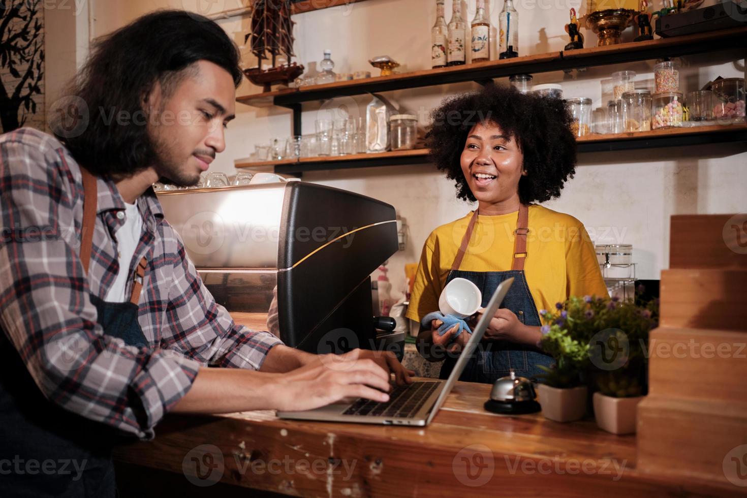 deux partenaires et amis de démarrage d'entreprise de café, une femme afro-américaine et des baristas thaïlandais discutent et sourient joyeusement ensemble au comptoir du café, un emploi de service heureux et un entrepreneur de PME. photo