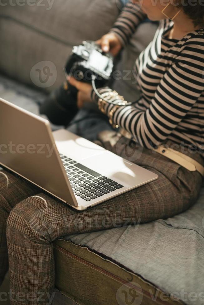 Gros plan sur la femme avec un ordinateur portable à l'aide d'un appareil photo reflex numérique moderne