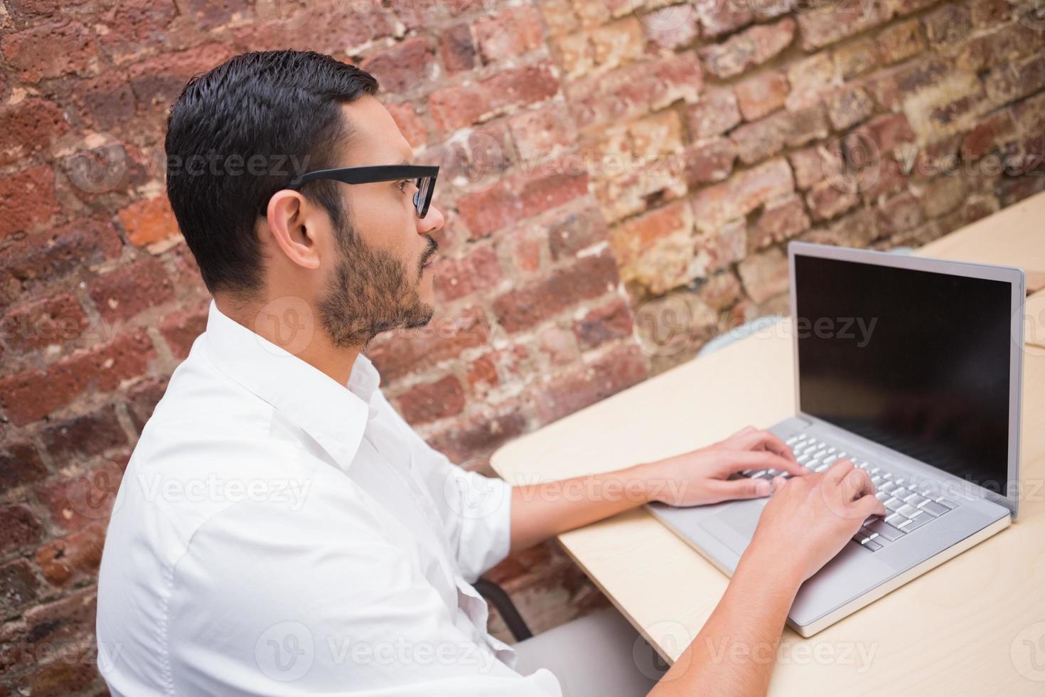 homme d'affaires concentré à l'aide d'un ordinateur portable au bureau photo