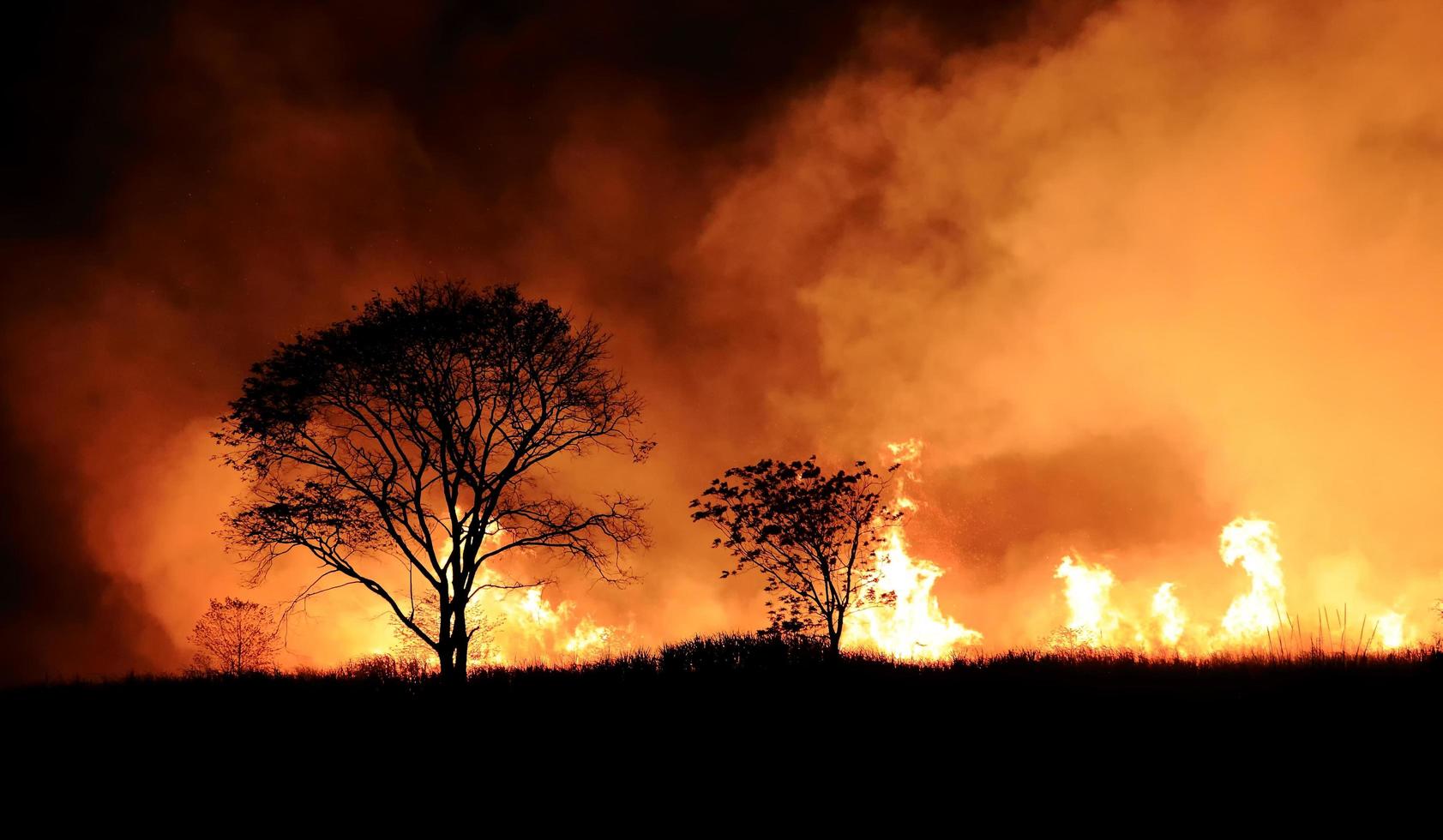 un feu de brousse brûlant de la fumée orange et rouge remplissait le ciel la nuit. photo