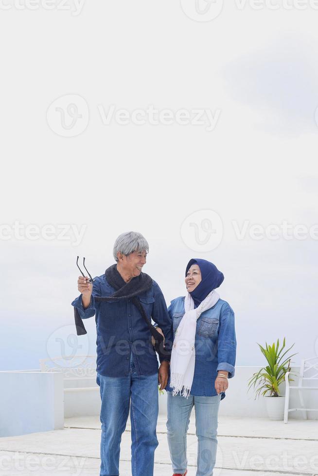 gros plan d'un couple de personnes âgées romantique dans un style décontracté marche ensemble tout en parlant et en souriant contre le ciel bleu. concept de mode de vie de couple de personnes âgées. photo