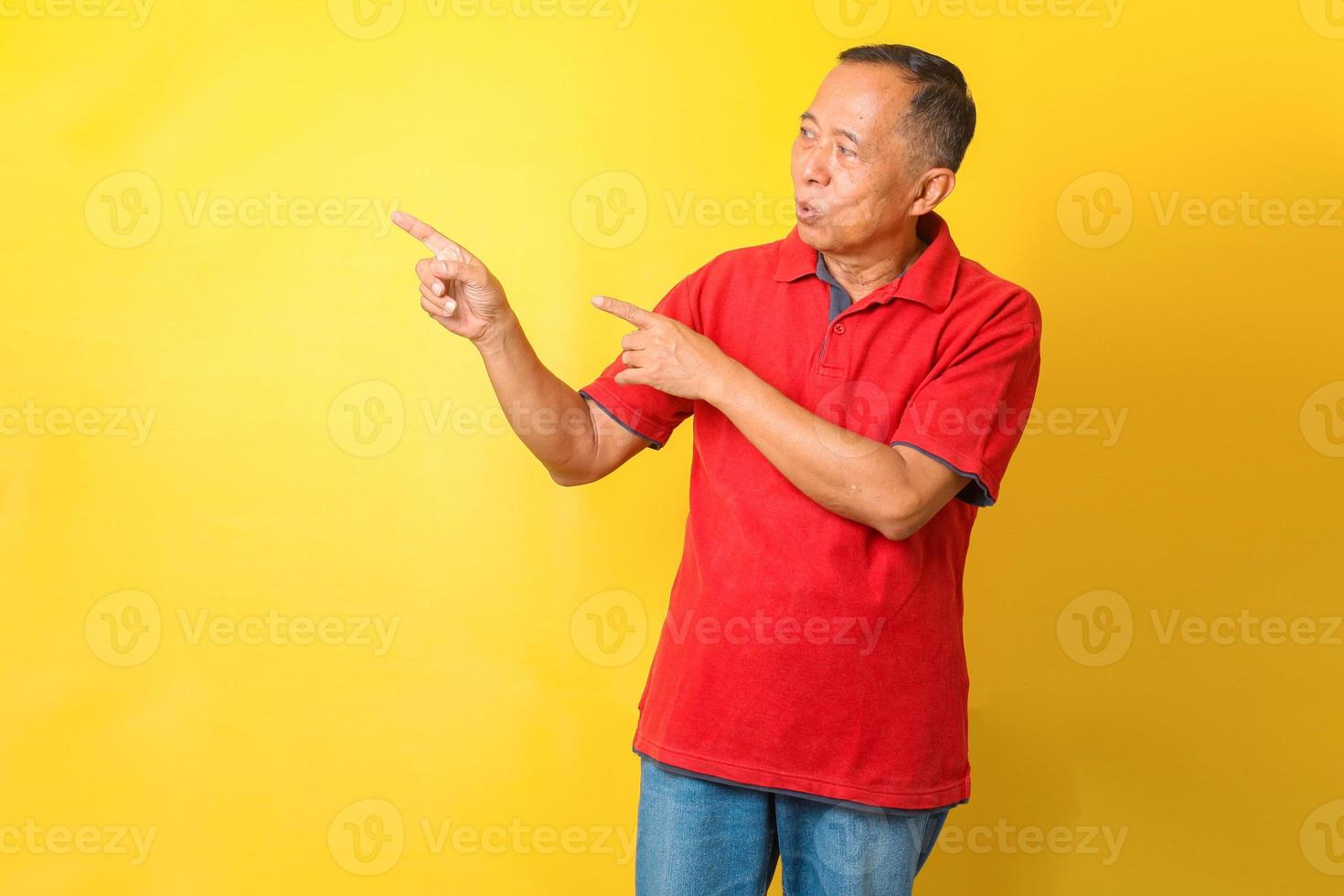 homme senior asiatique portant un t-shirt décontracté debout isolé sur fond jaune pointant avec la main et le doigt vers le côté avec une expression heureuse et naturelle sur le visage. photo