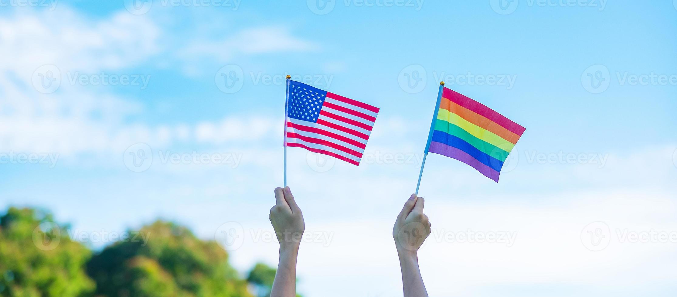 mains montrant l'arc-en-ciel lgbtq et le drapeau américain sur fond de nature. soutenir la communauté lesbienne, gay, bisexuelle, transgenre et queer et le concept du mois de la fierté photo