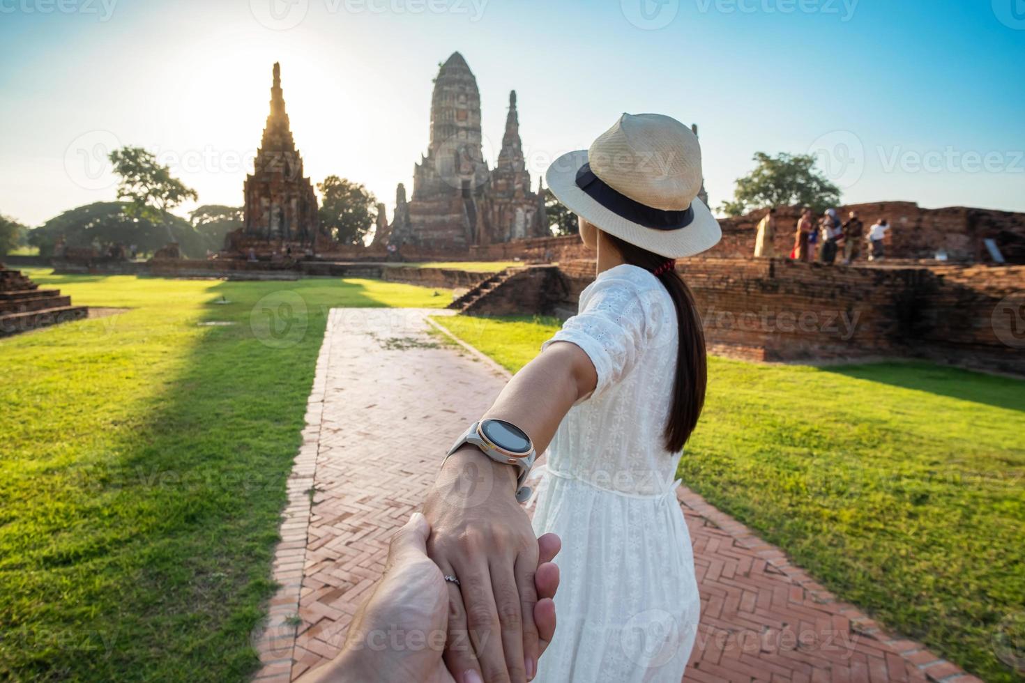 femme touristique en robe blanche tenant son mari à la main et marchant vers l'ancien stupa du temple wat chaiwatthanaram dans le parc historique d'ayutthaya, été, ensemble, suivez-moi, voyage en asie et en thaïlande photo