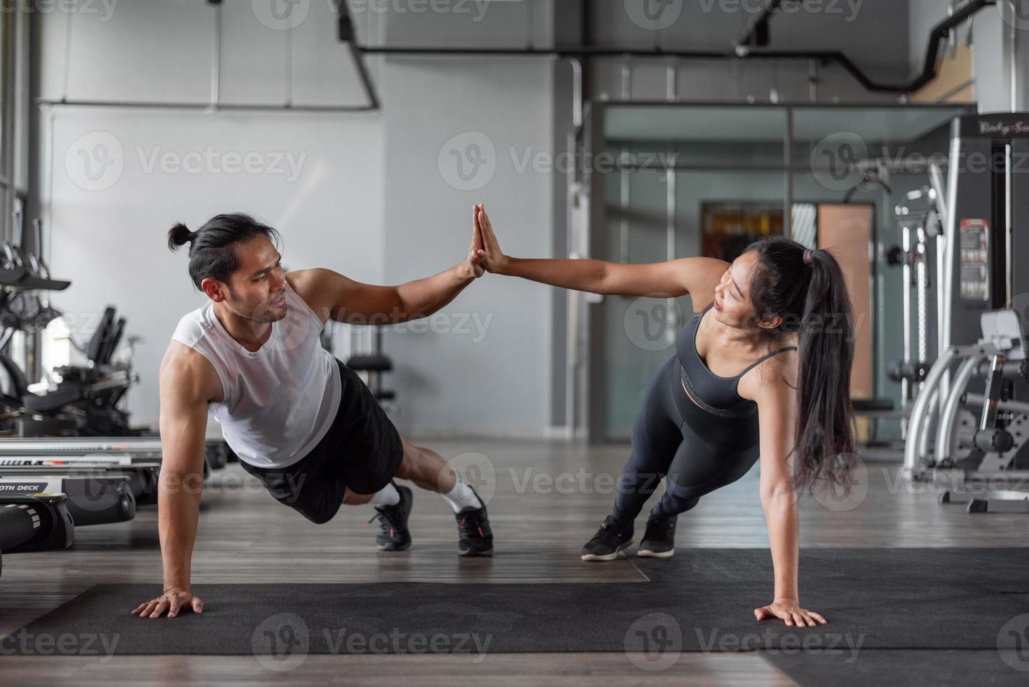 femme asiatique et homme asiatique s'exercent en fitness. couple en bonne santé faisant des exercices d'abs ensemble dans la salle de gym. photo