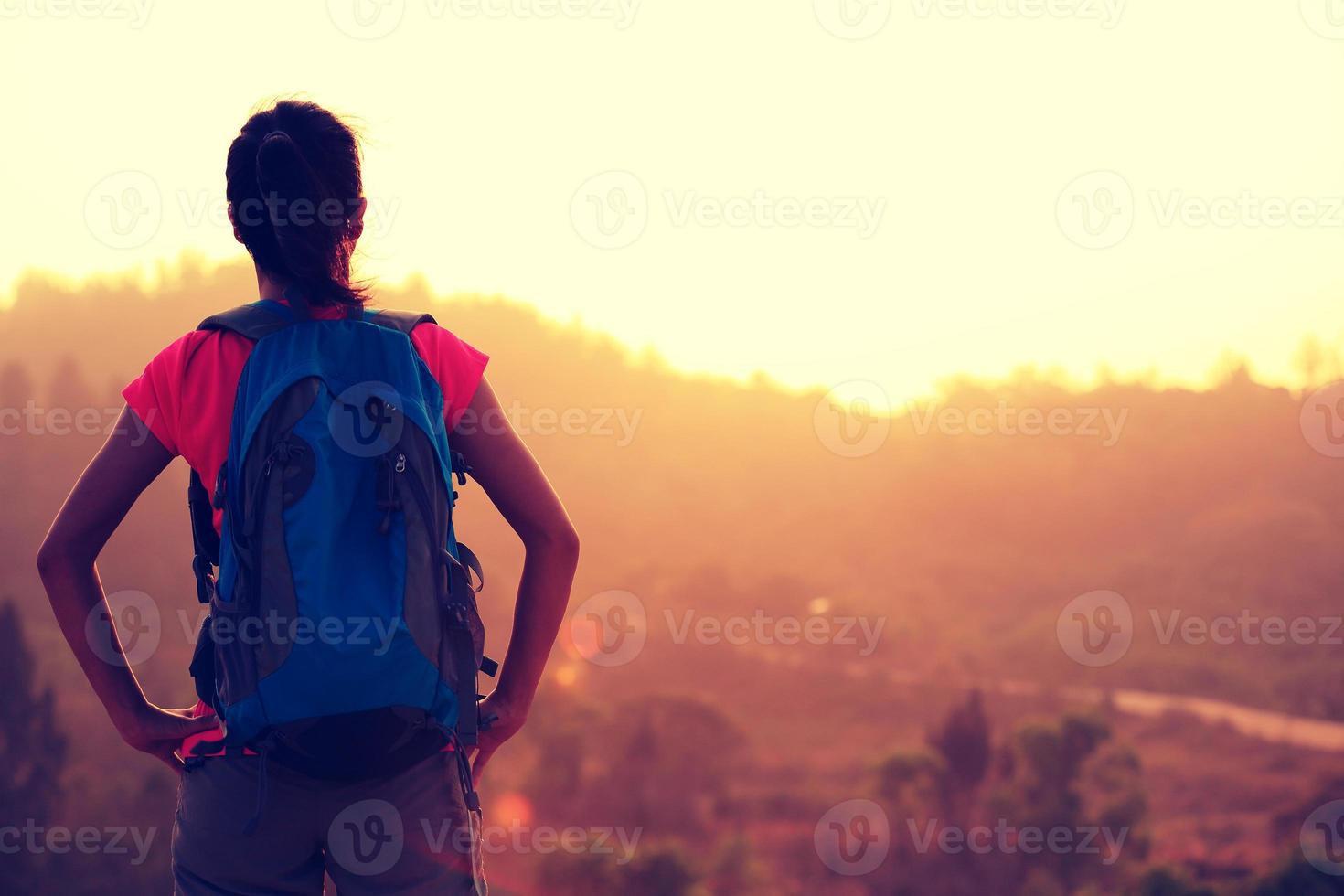 Jeune femme randonneur profiter de la vue sur le sommet de la montagne au lever du soleil photo