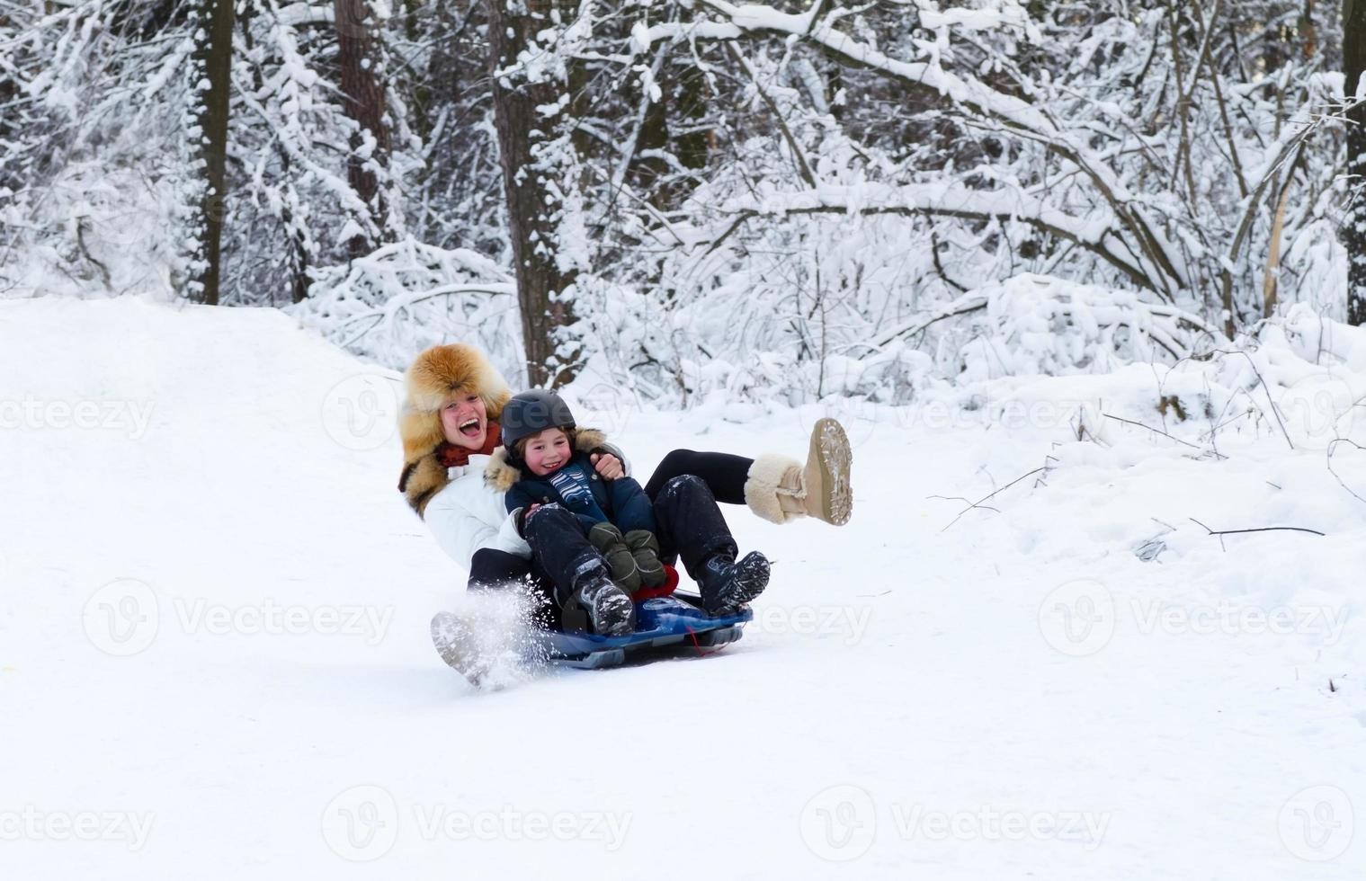 mère et fils profitant d'une promenade en traîneau sur une belle journée d'hiver photo