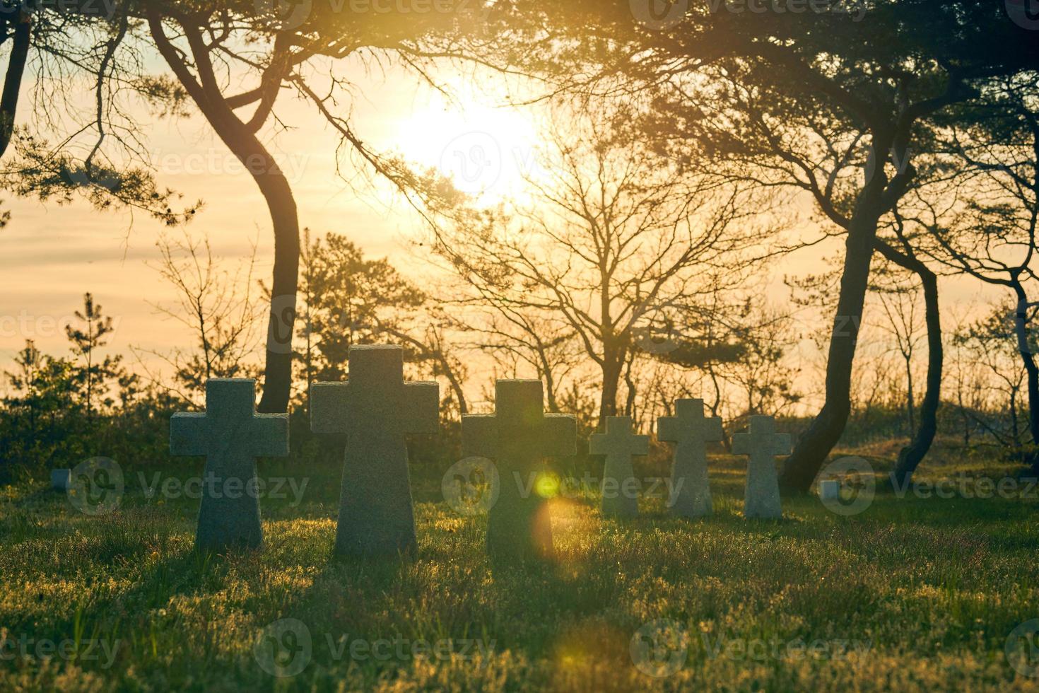 croix de pierre au coucher du soleil dans le cimetière militaire allemand, europe photo