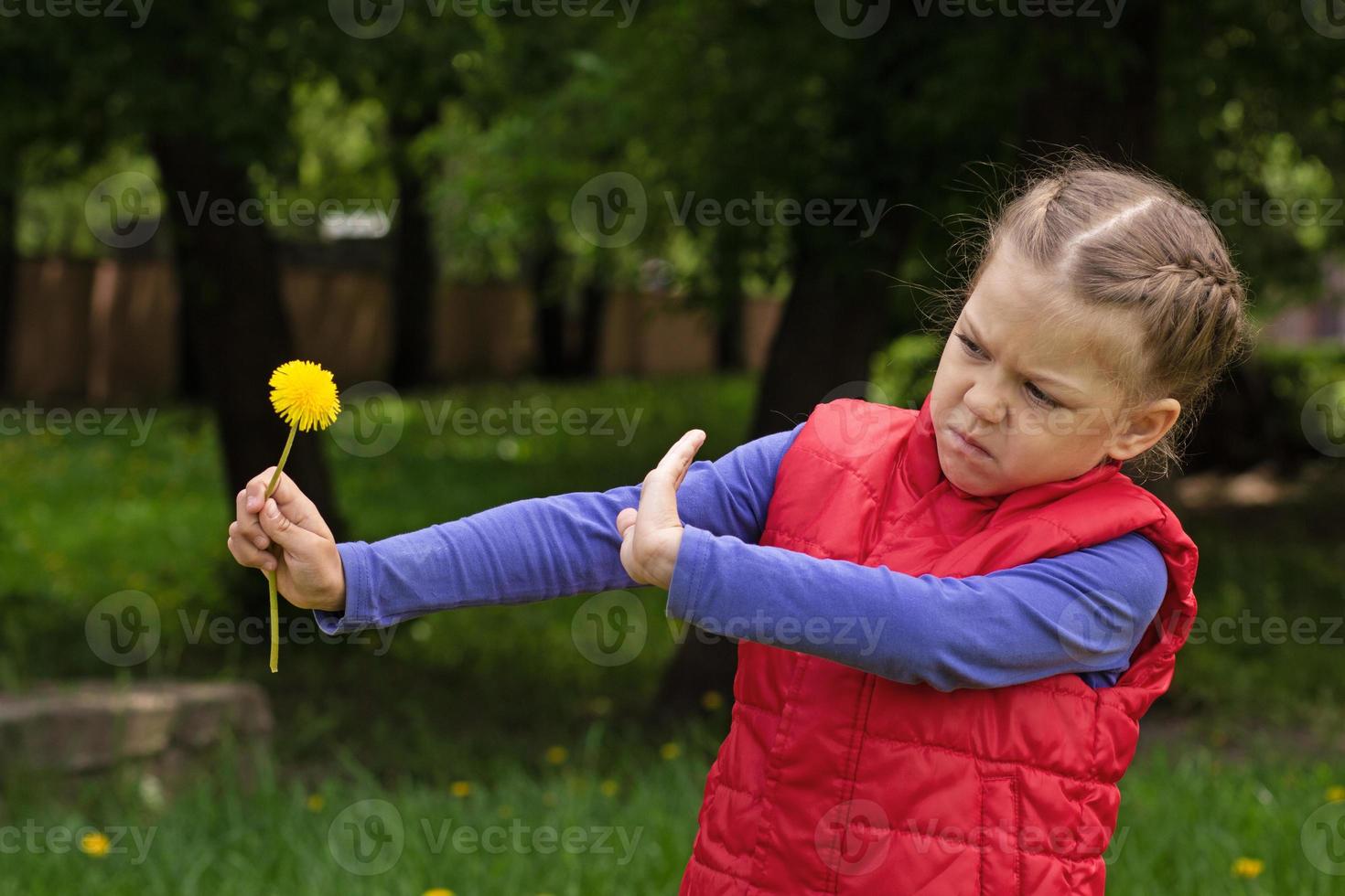 enfant tenant un pissenlit montré à la main contre une fleur photo