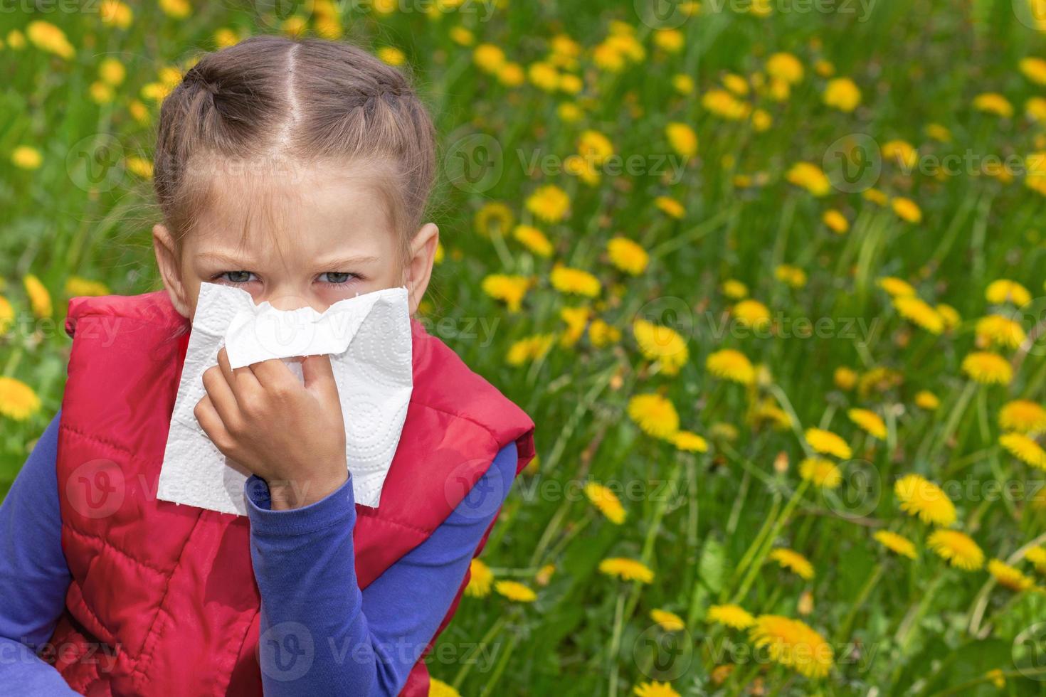 enfant tenant une serviette s'essuyant le nez à la main sur la pelouse de pissenlit photo