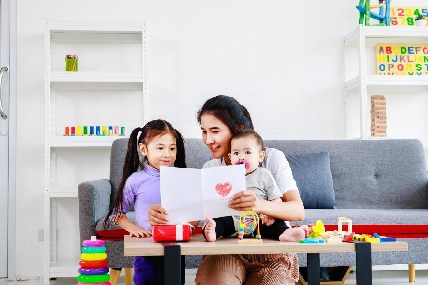 jolie fille envoie des cartes de maman d'amour à la mère et s'embrasse tout en prenant soin de bébé, concept de la fête des mères photo