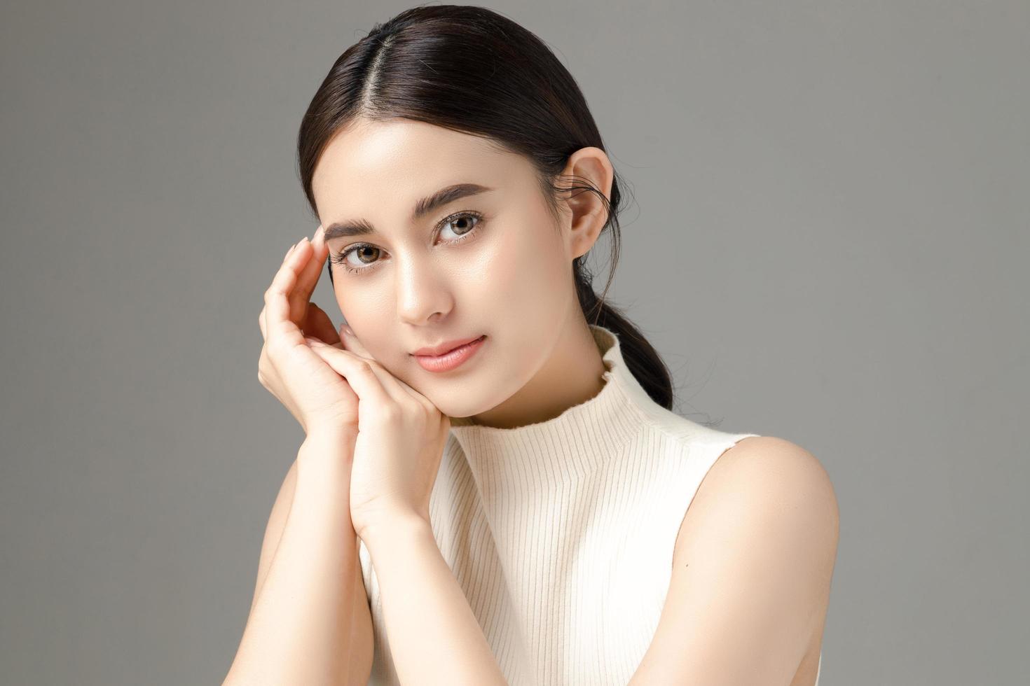 beau modèle de jeune femme asiatique avec une peau fraîche et propre parfaite sur fond gris. soins du visage, soins du visage, cosmétologie, chirurgie plastique, joli portrait de fille en studio. photo