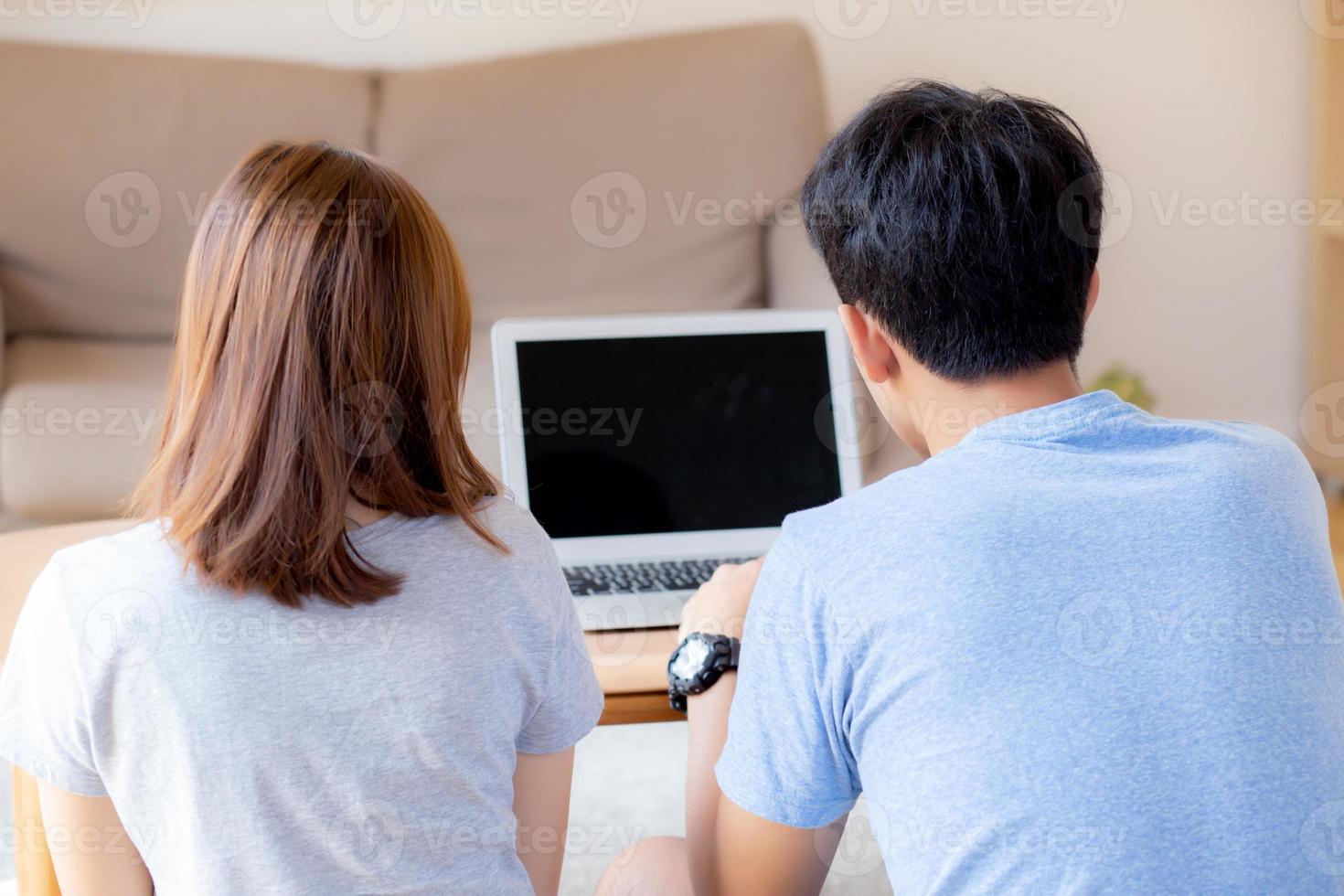 vue arrière d'un jeune couple asiatique travaillant sur un ordinateur portable avec écran vierge, planification familiale et recherche de contenu ensemble, homme et femme à la recherche d'un concept d'ordinateur, d'entreprise et de communication. photo