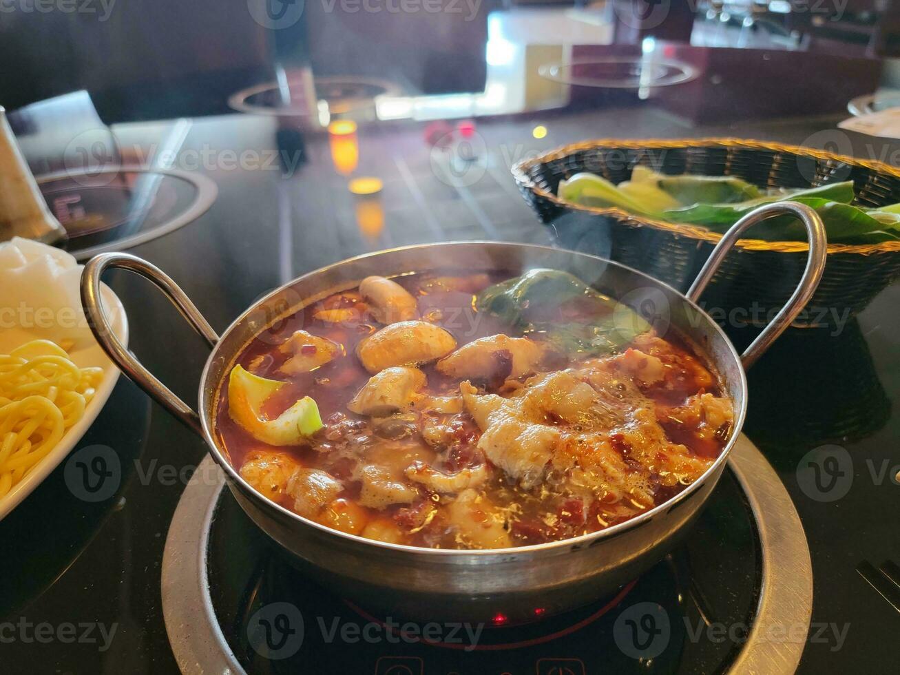 fondue chinoise avec bouillon épicé dans un bol avec de la viande et des légumes photo