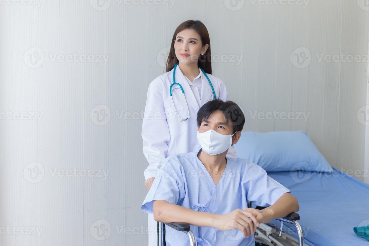 femme médecin asiatique parlant avec un patient homme qui porte un masque facial sur ses symptômes de santé alors qu'il est assis sur un fauteuil roulant à l'hôpital. photo