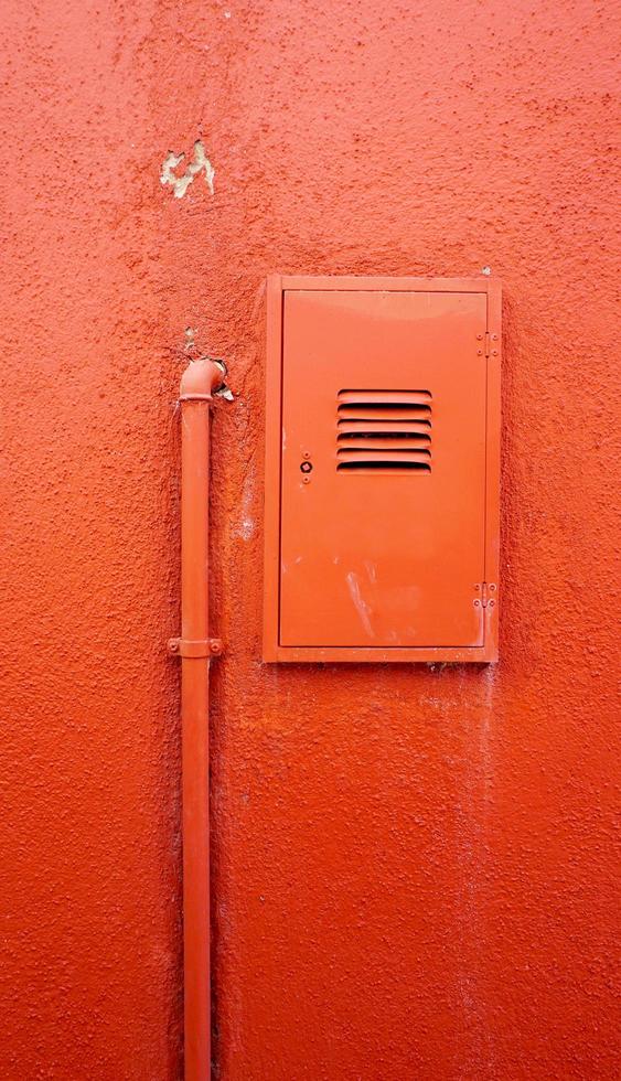 tuyau métallique vertical et boîtier électrique sur mur de couleur orange photo